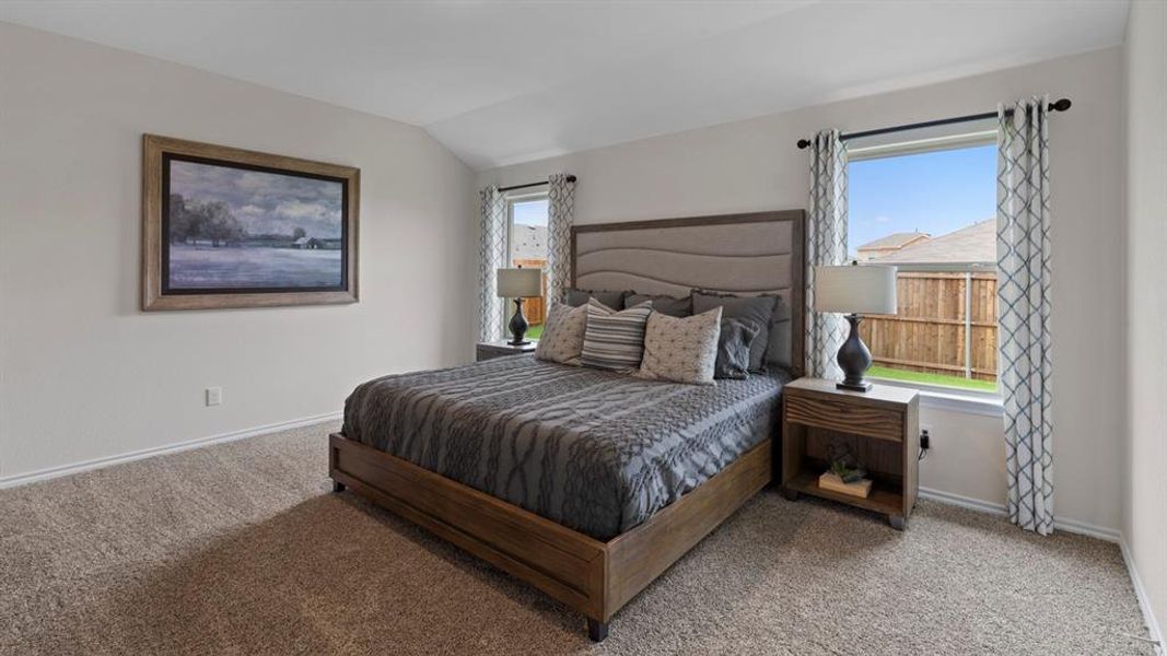 Bedroom with light colored carpet and lofted ceiling