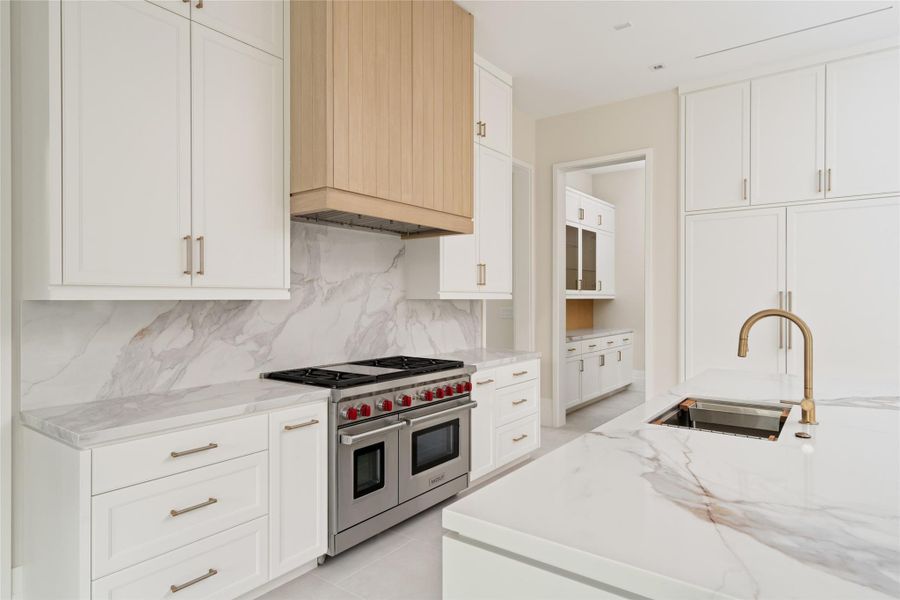Quartzite-clad surfaces and a Wolf range anchor the space, with a seamless connection to the mudroom beyond.