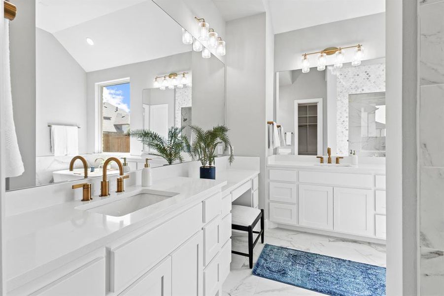 Bathroom with light marble finish floors, a marble finish shower, two vanities, vaulted ceiling, and recessed lighting
