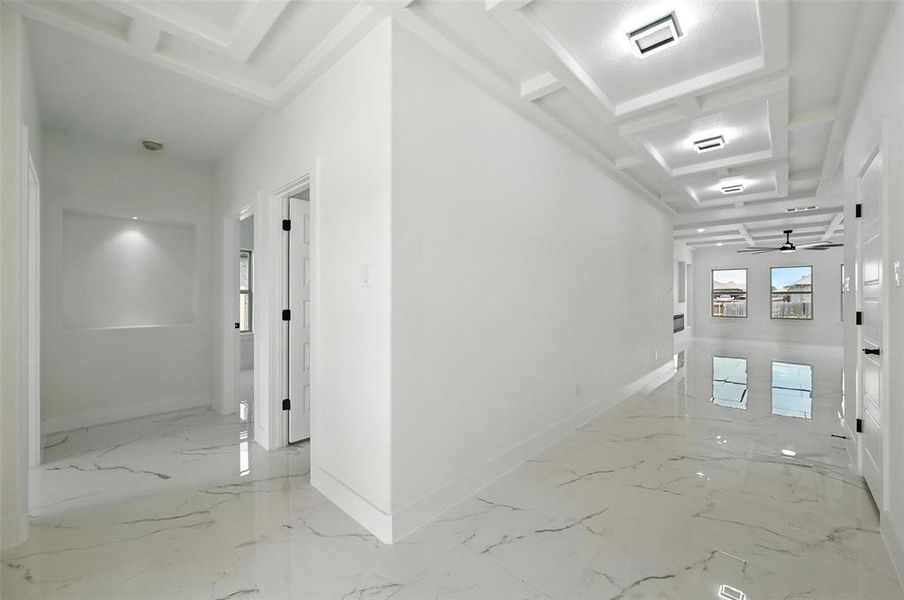 Hall with light marble finish floors, coffered ceiling, and beam ceiling