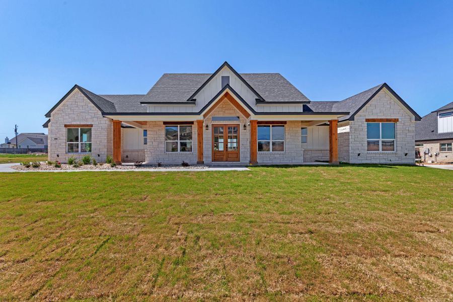 Modern farmhouse with covered porch, a front lawn, stone siding, roof with shingles, and french doors Modern farmhouse with covered porch, a front lawn, stone siding, roof with shingles, and french doors