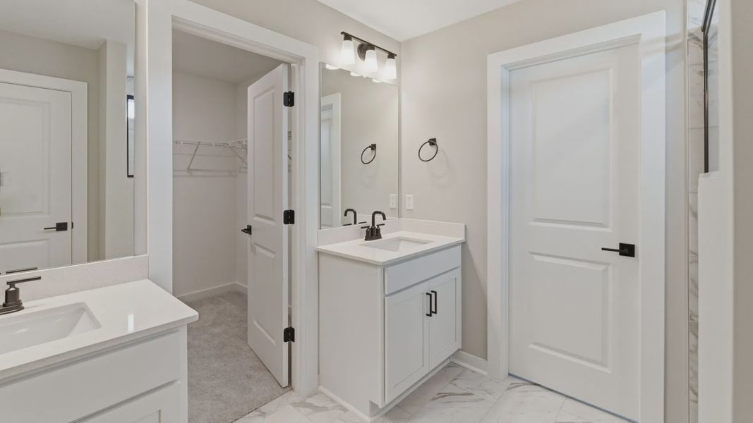 Bathroom with dual vanity and access to primary closet