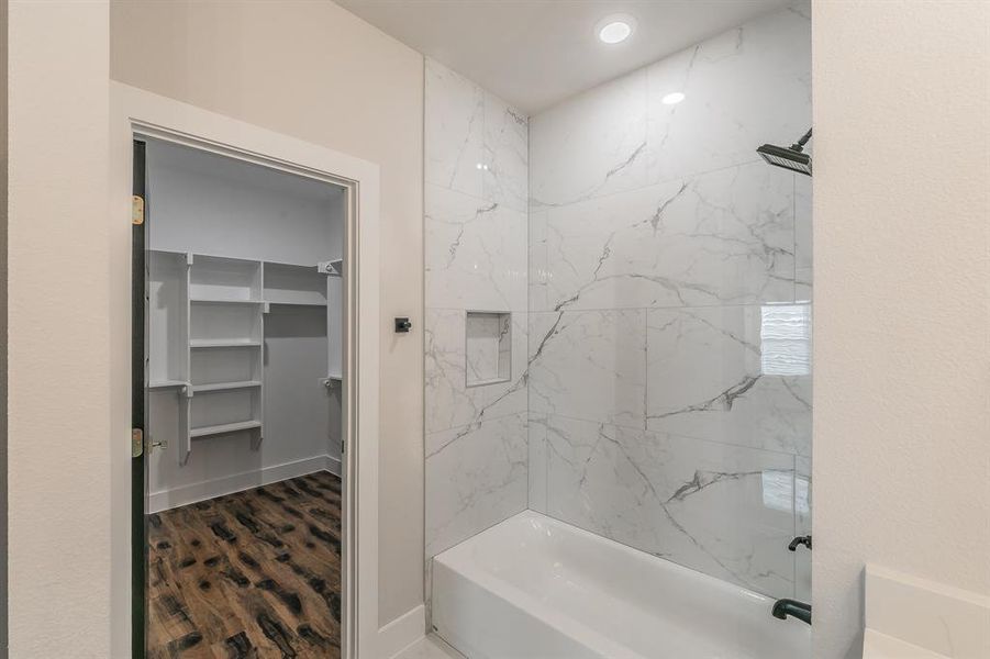 Bathroom with hardwood / wood-style floors and tiled shower / bath combo