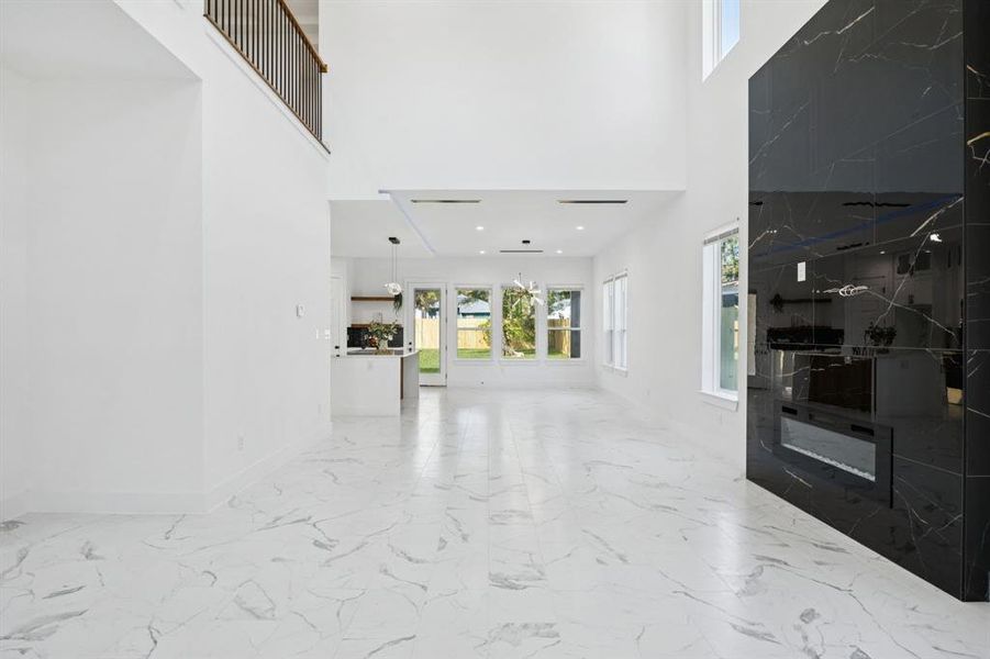 Entryway featuring light marble finish floors and a towering ceiling