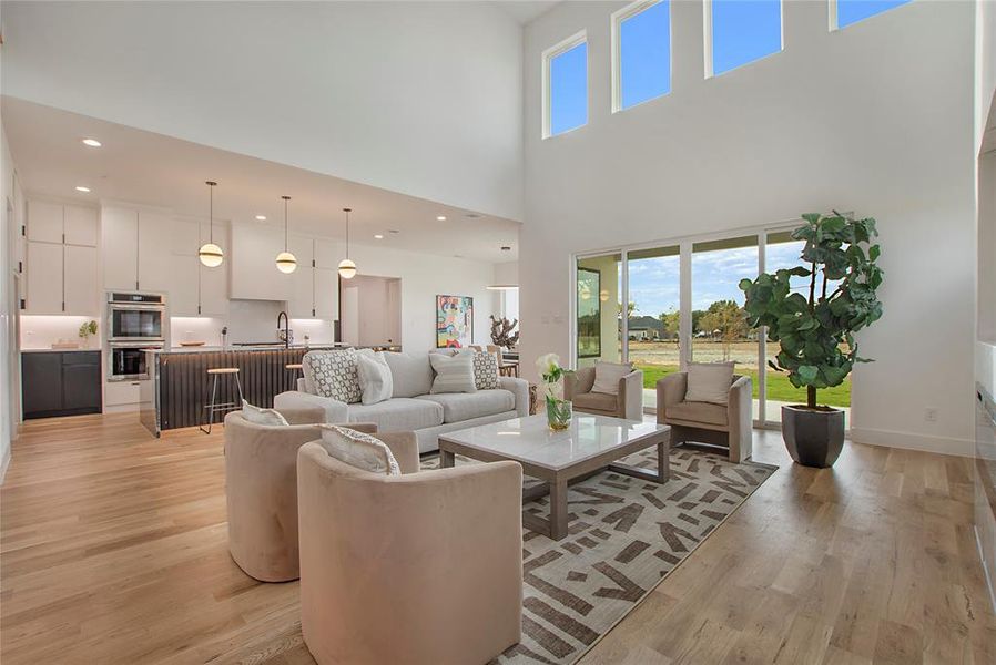 Living room with sink, light hardwood / wood-style flooring, and a towering ceiling