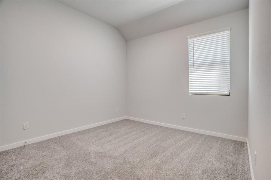 Empty room with light colored carpet and lofted ceiling