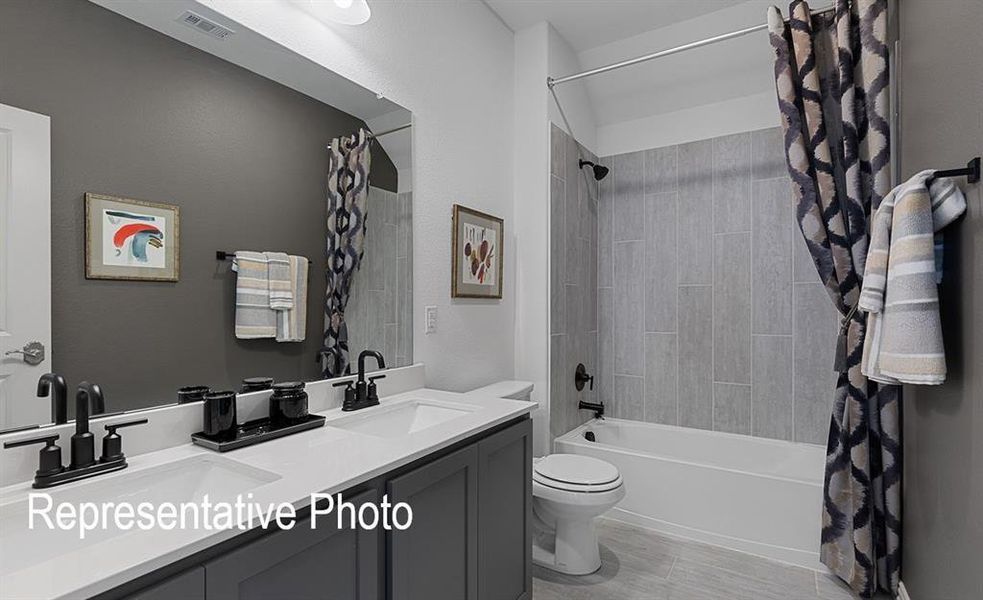 Full bathroom featuring shower / bath combo with shower curtain, vanity, and toilet