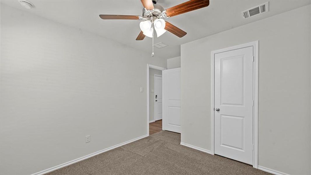 Unfurnished bedroom with dark carpet and a ceiling fan