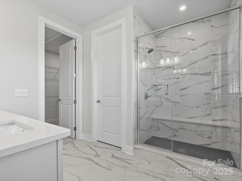 Oversized walk-in shower with convenient seat and tile pan.