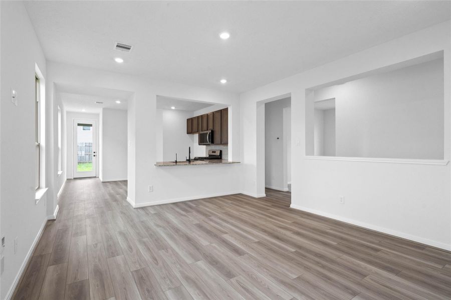 Designed for comfort and connection, this spacious open-concept great room boasts soaring ceilings, large windows, recessed lighting, and vinyl plank flooring, seamlessly merging with the stunning kitchen for easy living and entertaining.