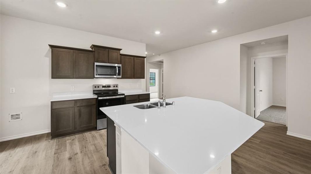 Contemporary kitchen featuring an expansive island with an undermount sink and a stainless steel faucet Contemporary kitchen featuring an expansive island with an undermount sink and a stainless steel faucet