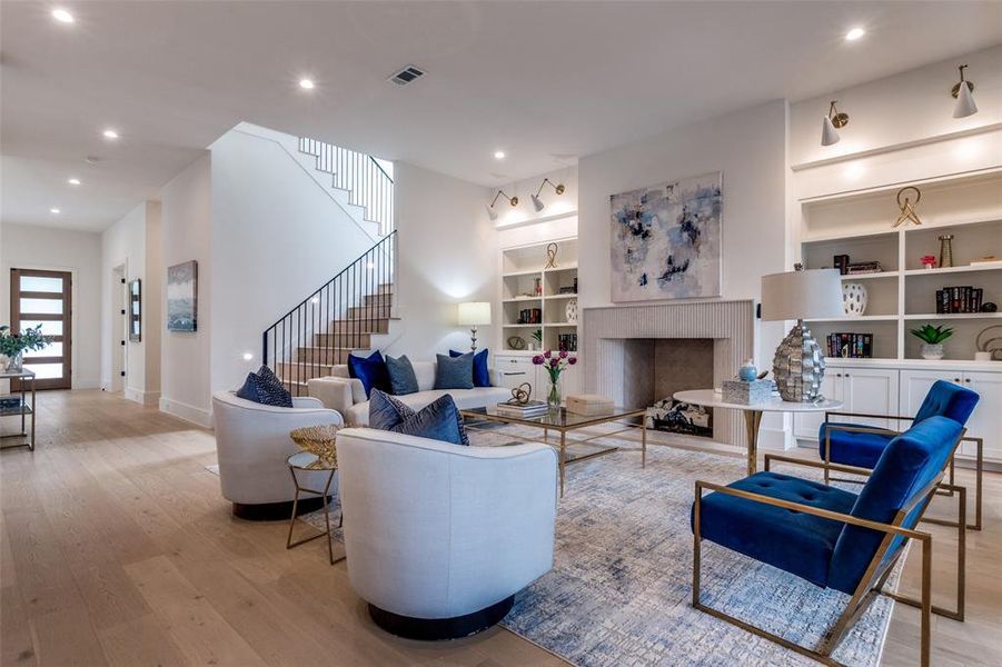 Living area featuring stairs, wood finished floors, visible vents, built in features, and baseboards Living area featuring stairs, wood finished floors, visible vents, built in features, and baseboards