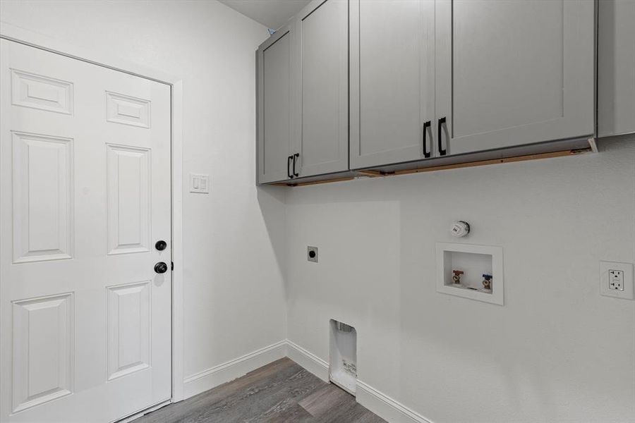 Clothes washing area featuring electric dryer hookup, washer hookup, cabinets, and wood-type flooring