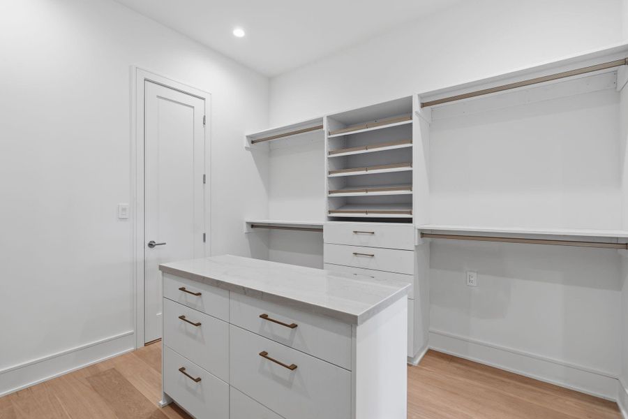 Custom closet system with stone-topped island and LED lighting system.