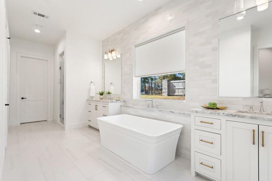 Bathroom featuring a soaking tub, two vanities, backsplash, a shower stall, and recessed lighting