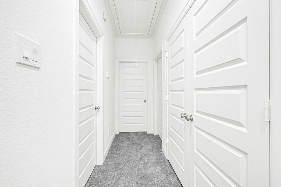 This photo shows a bright, modern hallway with white paneled doors and textured walls. The space is carpeted in a neutral gray, offering a clean and inviting look. This photo shows a bright, modern hallway with white paneled doors and textured walls. The space is carpeted in a neutral gray, offering a clean and inviting look.