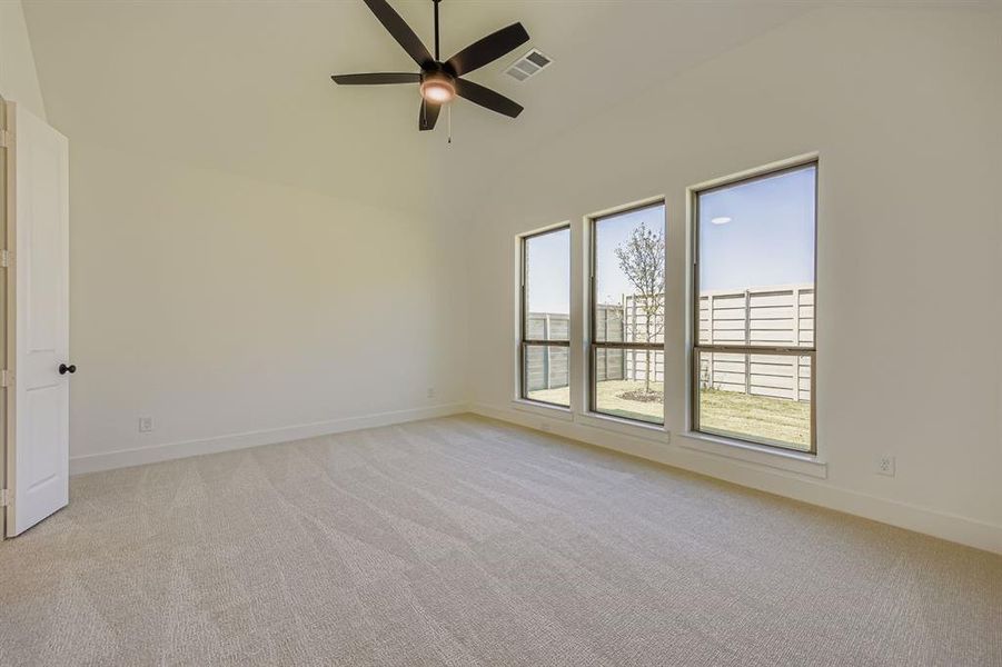 Unfurnished room with light carpet, a ceiling fan, and high vaulted ceiling Unfurnished room with light carpet, a ceiling fan, and high vaulted ceiling