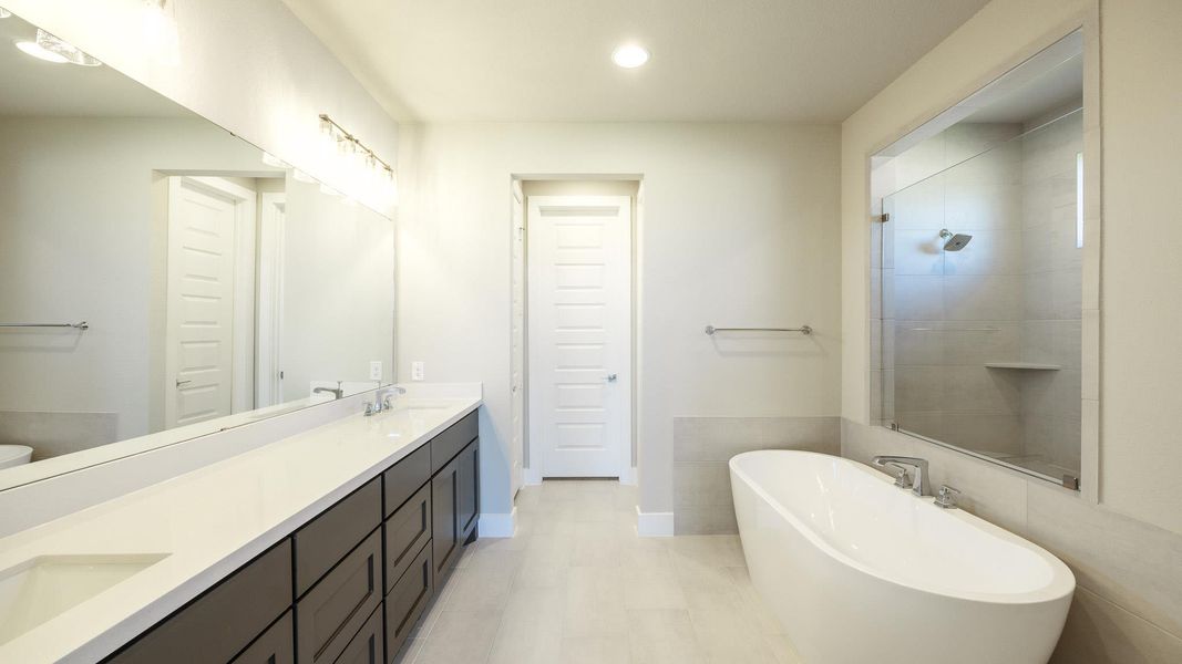Bathroom with a freestanding tub, double vanity, recessed lighting, and a tile shower Bathroom with a freestanding tub, double vanity, recessed lighting, and a tile shower
