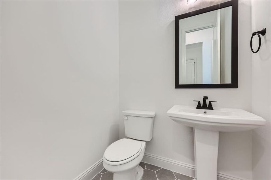 Bathroom featuring toilet, sink, and tile patterned floors