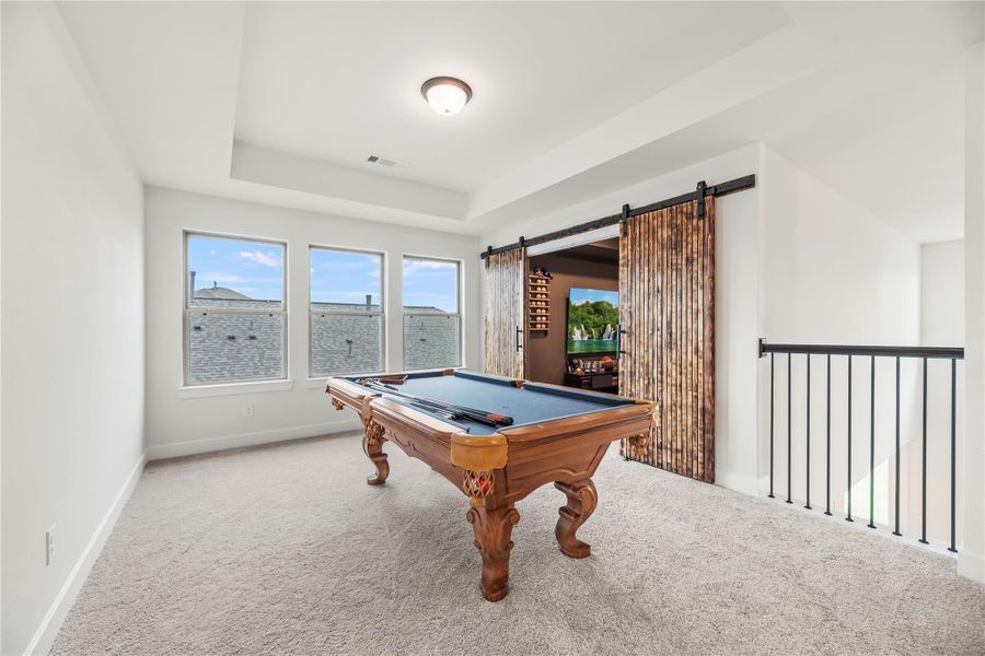 It's all fun and games in this spacious game room with plush carpet, a raised tray ceiling, views of the family room below, and rich wood sliding doors that open to the media room.