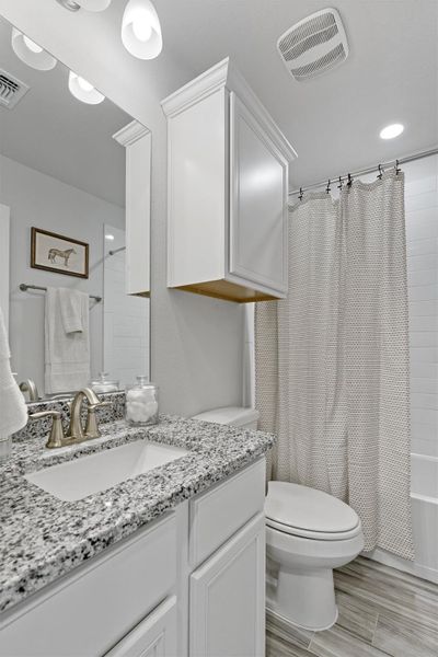 Full bath featuring vanity, shower / bathtub combination with curtain, and wood finish floors