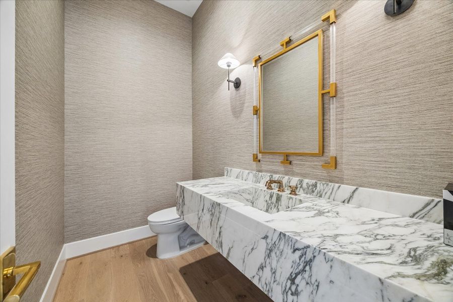 Powder bathroom has floating marble countertop and grasscloth wall covering.