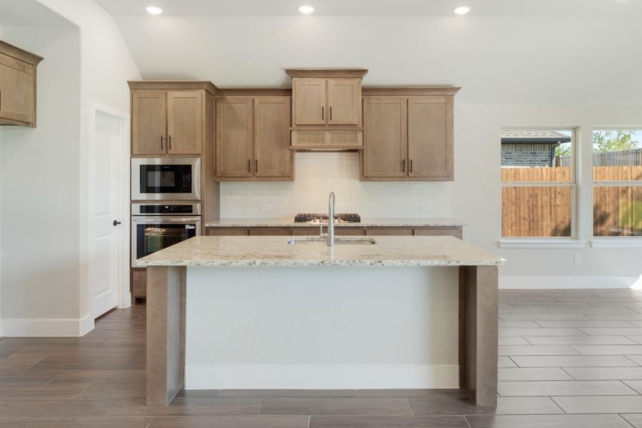 Kitchen with granite island, tan wood cabinets, and stainless steel double oven and microwave Kitchen with granite island, tan wood cabinets, and stainless steel double oven and microwave
