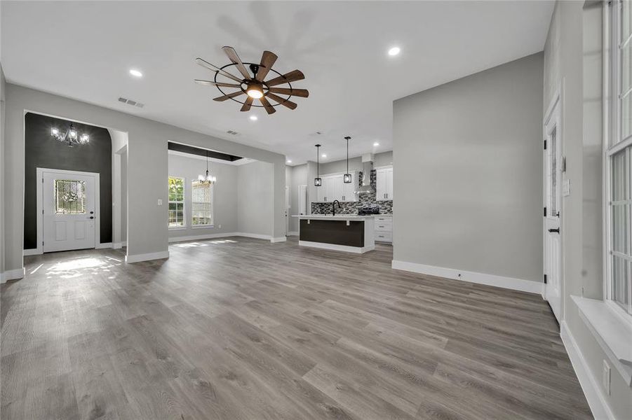 Unfurnished living room featuring sink, ceiling fan with notable chandelier, and light hardwood / wood-style floors