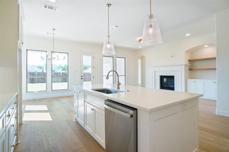 Kitchen featuring stainless steel dishwasher, light wood-style floors, arched walkways, white cabinets, and recessed lighting Kitchen featuring stainless steel dishwasher, light wood-style floors, arched walkways, white cabinets, and recessed lighting