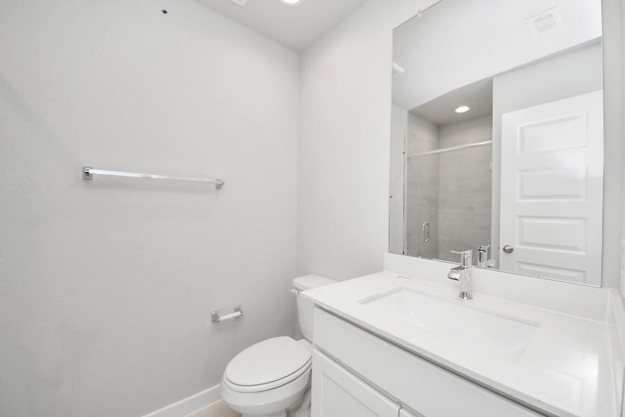 Secondary bath features tile flooring, bath/shower combo with tile surround, light stained wood cabinets, beautiful light countertop. Sample photo of completed home with similar floor plan. Actual colors and selections may vary.