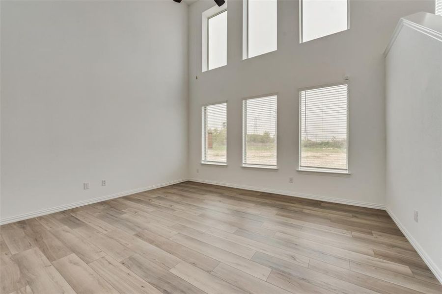 Empty room with light wood-type flooring, a healthy amount of sunlight, and ceiling fan