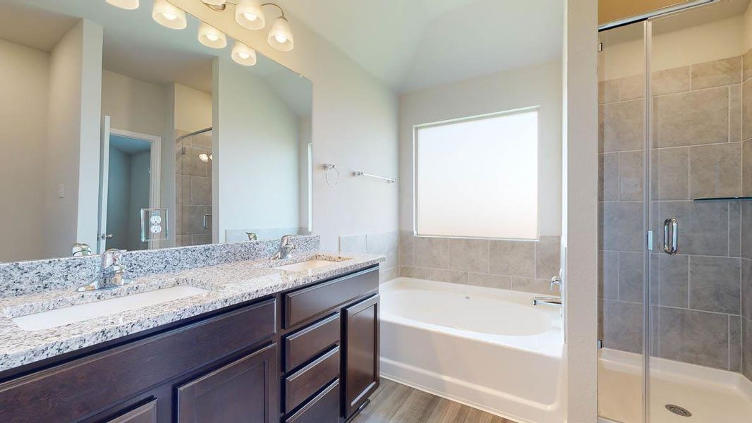 Bathroom featuring a dual vanity with a speckled countertop, undermount sinks, and dark wood cabinetry