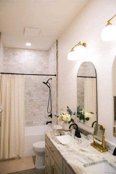 3rd full bathroom floor to ceiling tile with Fantasy Brown Satin marble, 2 sinks, and a shower/tub combo.