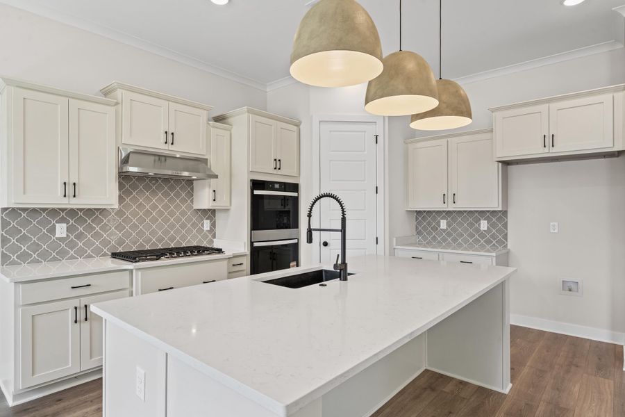 Kitchen featuring tasteful backsplash, light stone countertops, dark wood-style flooring, ornamental molding, and recessed lighting Kitchen featuring tasteful backsplash, light stone countertops, dark wood-style flooring, ornamental molding, and recessed lighting