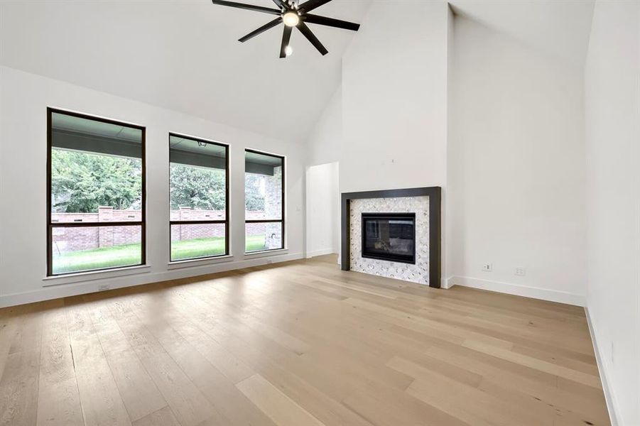Spacious room featuring vaulted ceilings, light wood-finish flooring, and a modern fireplace with a patterned stone surround Spacious room featuring vaulted ceilings, light wood-finish flooring, and a modern fireplace with a patterned stone surround