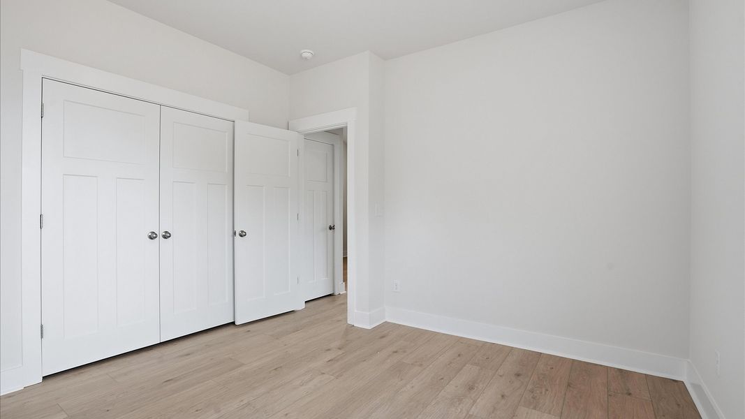 Timeless secondary bedroom offering hardwood flooring and a stylish walk-in closet