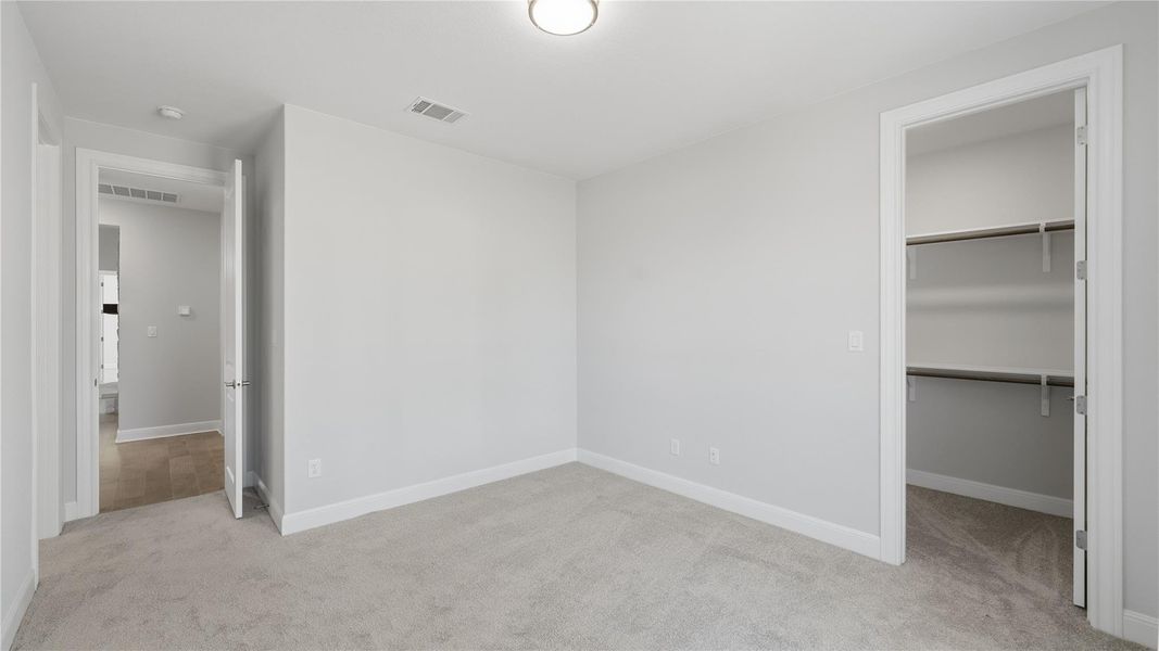 Unfurnished bedroom with a spacious closet and light colored carpet Unfurnished bedroom with a spacious closet and light colored carpet