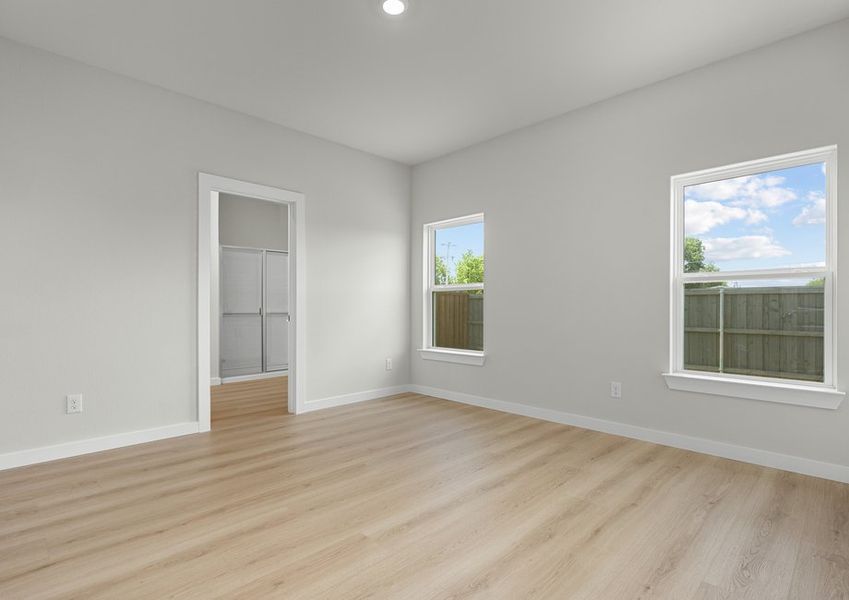 Large master bedroom has two windows and light flooring to keep the room bright.