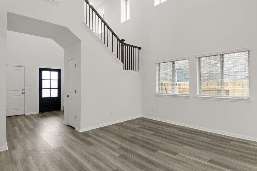 Unfurnished living room featuring healthy amount of natural light, dark wood-type flooring, and a high ceiling Unfurnished living room featuring healthy amount of natural light, dark wood-type flooring, and a high ceiling