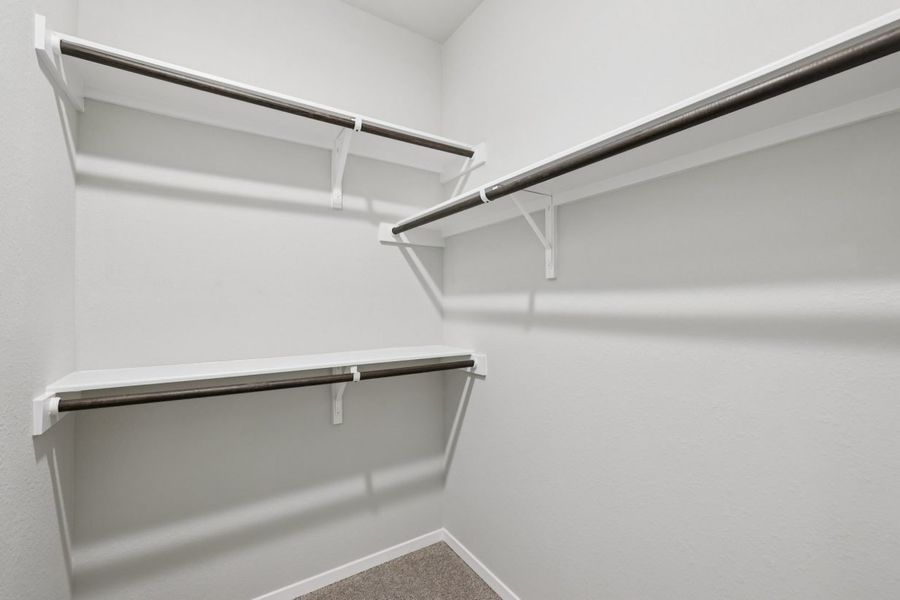 Image of a closet with light grey walls, white shelves and wooden rods