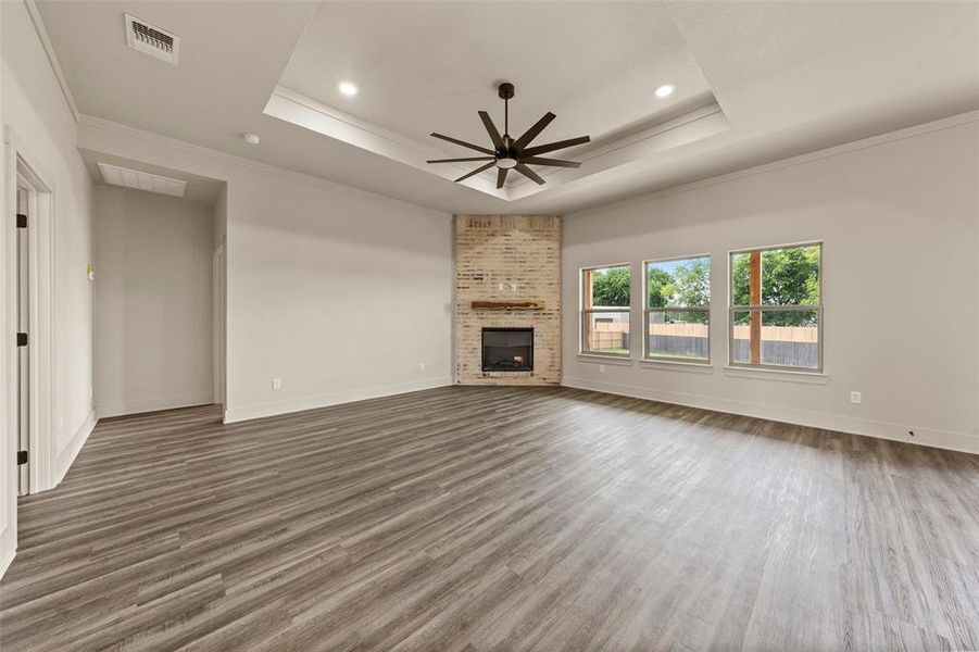 Spacious interior showcasing wood-finish flooring, a tray ceiling with recessed lighting, and a modern ceiling fan Spacious interior showcasing wood-finish flooring, a tray ceiling with recessed lighting, and a modern ceiling fan