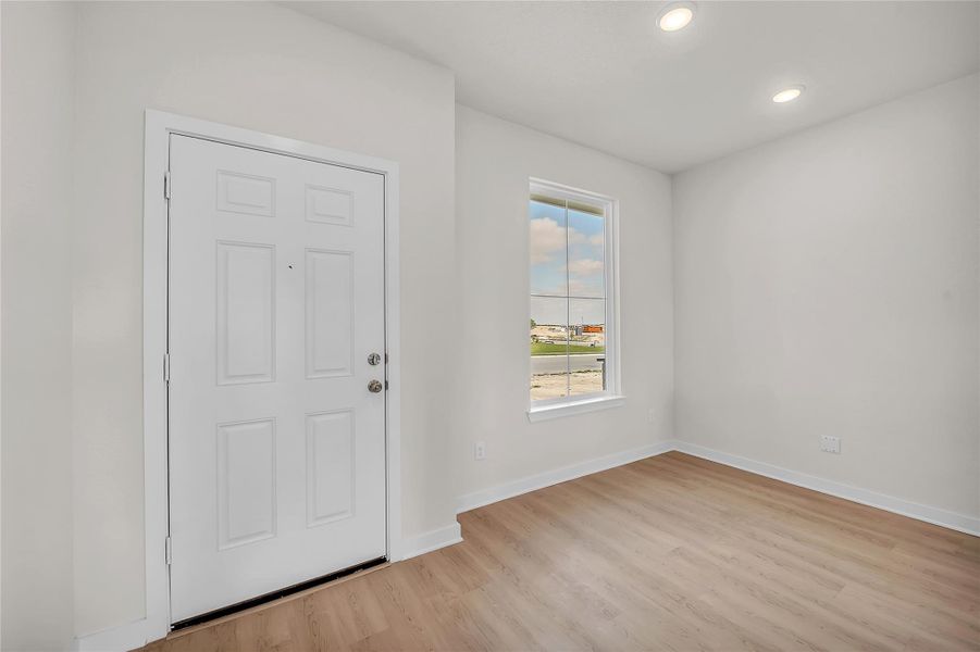 Entryway with light wood finished floors and recessed lighting