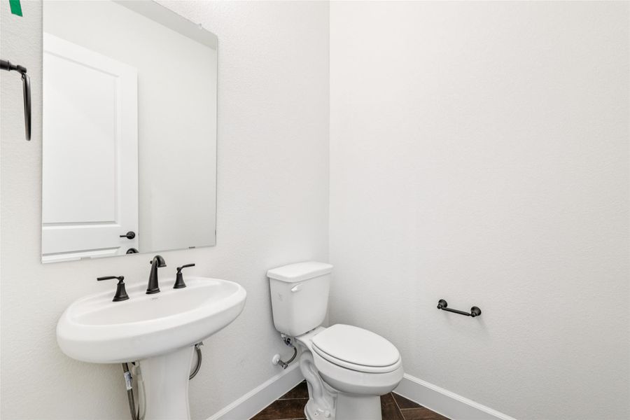 Half bath with baseboards and toilet