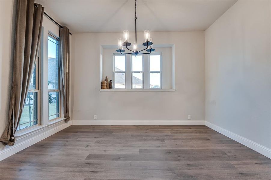 Spare room with a chandelier, healthy amount of natural light, and wood finished floors Spare room with a chandelier, healthy amount of natural light, and wood finished floors