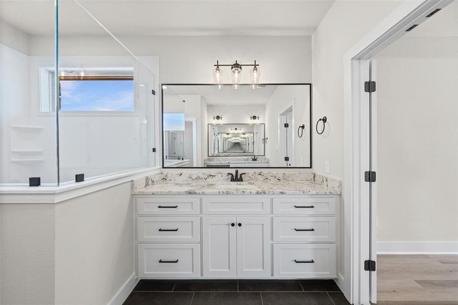 Full bath featuring vanity and dark tile patterned flooring
