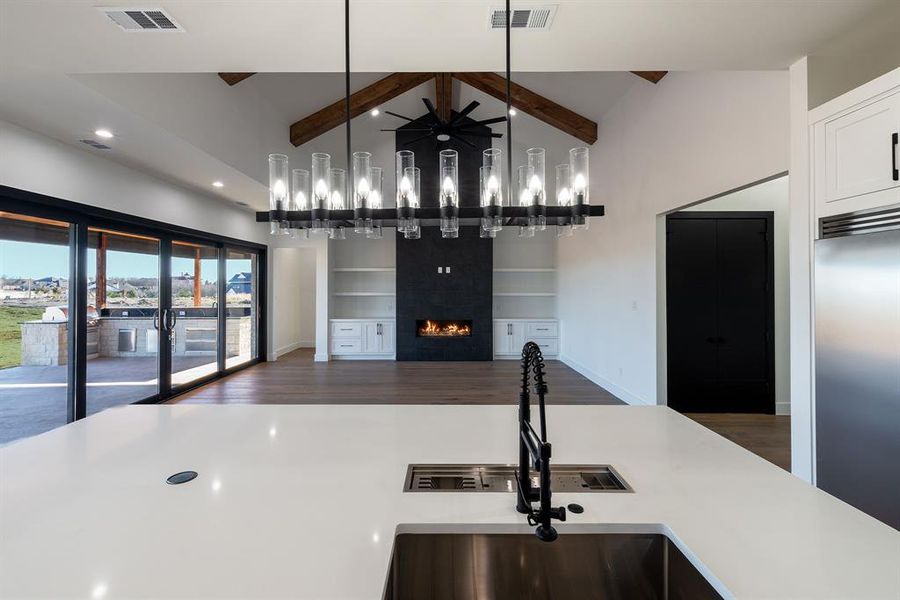 Kitchen with built in fridge, dark hardwood / wood-style floors, high vaulted ceiling, hanging light fixtures, and ceiling fan