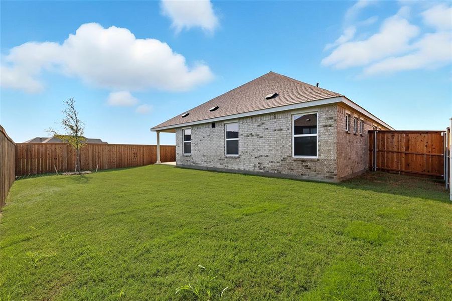 Rear view of property featuring a fenced backyard, brick siding, and a shingled roof Rear view of property featuring a fenced backyard, brick siding, and a shingled roof