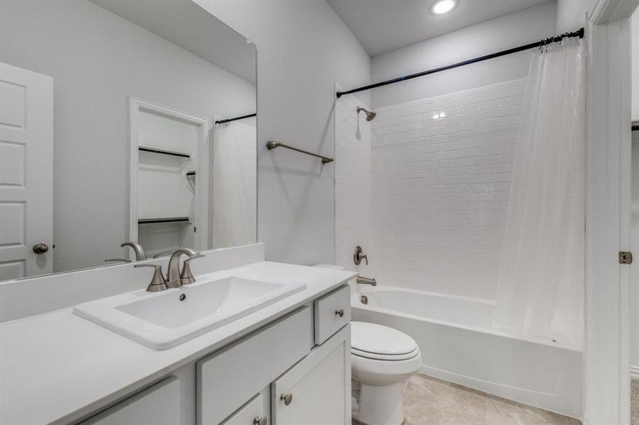 Bathroom featuring tile patterned floors, vanity, toilet, and shower / tub combo