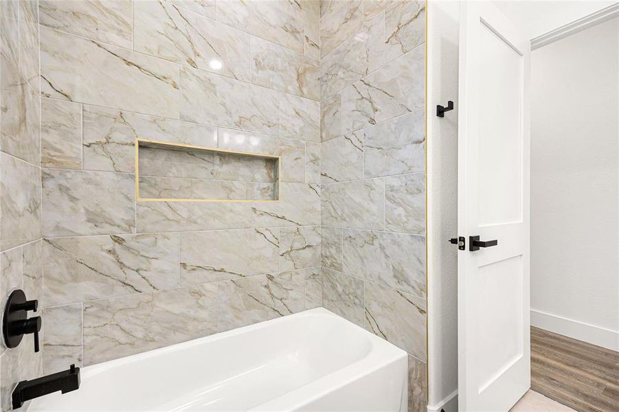 Bathroom #2-This modern bathroom features a sleek white vanity with black fixtures, a large arched mirror, and a glass-enclosed shower. The neutral tones and minimalist design create a clean and inviting space.