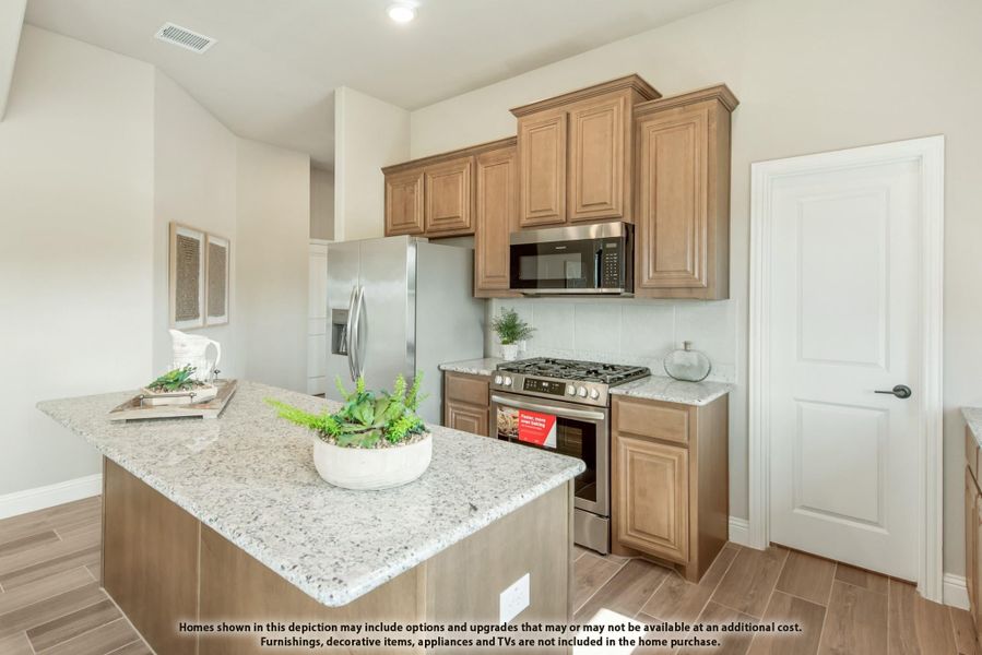 Kitchen with granite island, wood cabinets, and stainless steel appliances including gas range and refrigerator